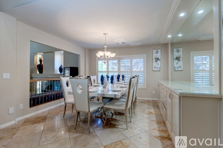 A dining room with a table set for four and a chandelier hanging from the ceiling.