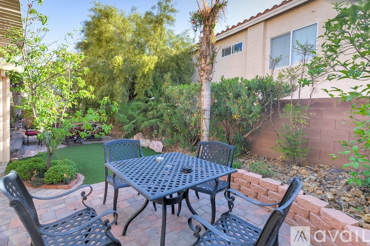 A patio with a table and chairs surrounded by a brick wall and trees.