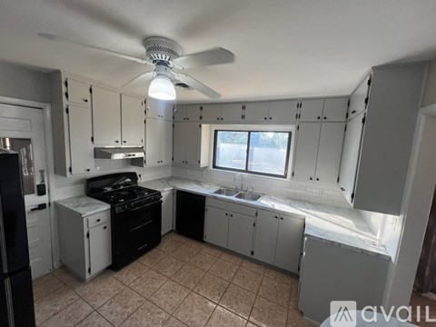 A kitchen with white cabinets and black appliances.