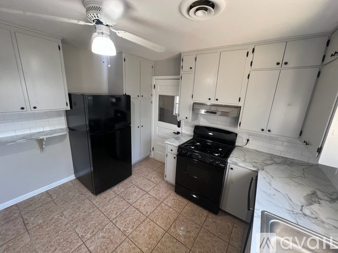 A kitchen with black appliances and white cabinets.