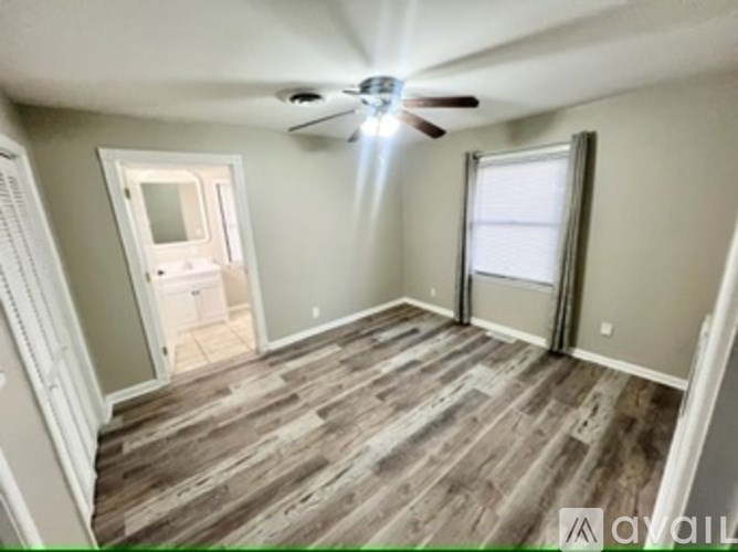 A room with a ceiling fan and wooden flooring.