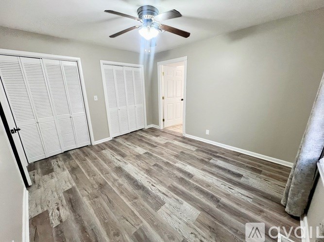 A room with a ceiling fan and wooden flooring.