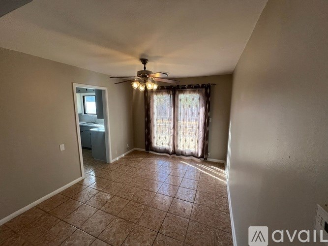 A room with a ceiling fan and a window with curtains.