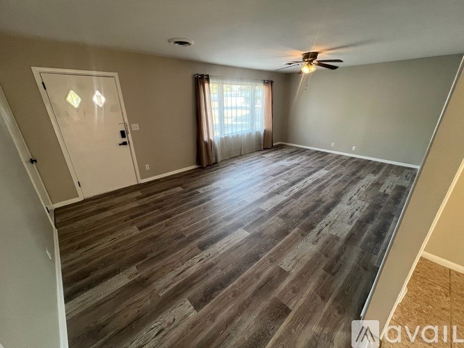 A spacious room with wooden flooring and a ceiling fan.