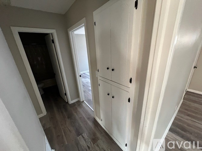 A room with a white cabinet and a doorway leading to another room.