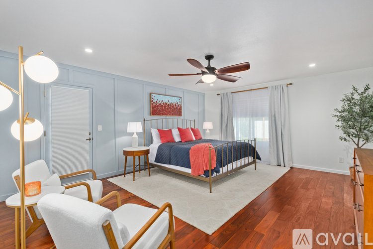 A bedroom with a bed, chair, and ceiling fan.