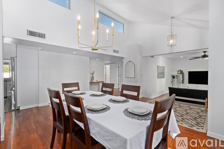 A dining room with a table set for six and a chandelier hanging from the ceiling.