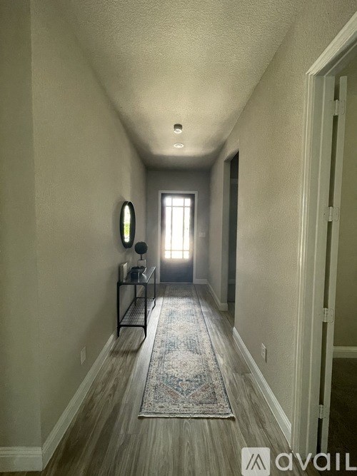 A hallway with a rug and a mirror on the wall.