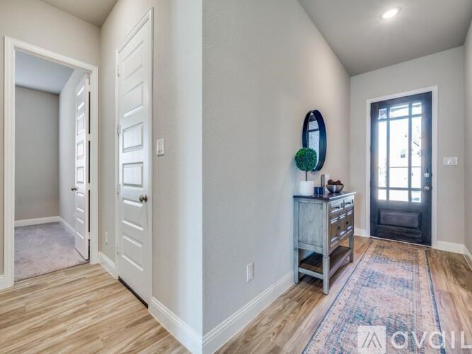 A hallway with a white door and a rack of clothes.