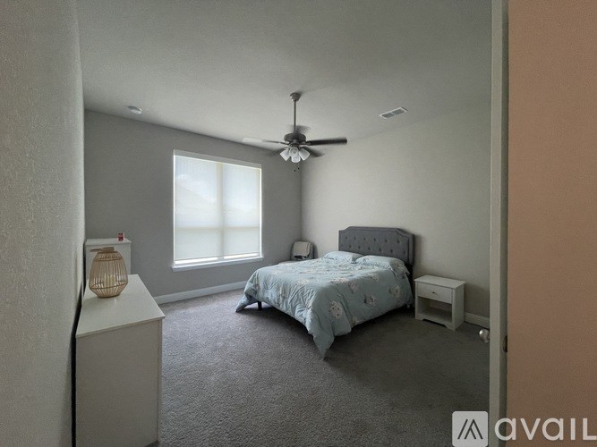 A bedroom with a bed, nightstand, and window.