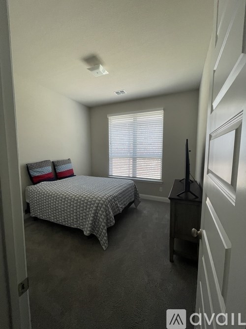 A bedroom with a bed, nightstand, and window with blinds.