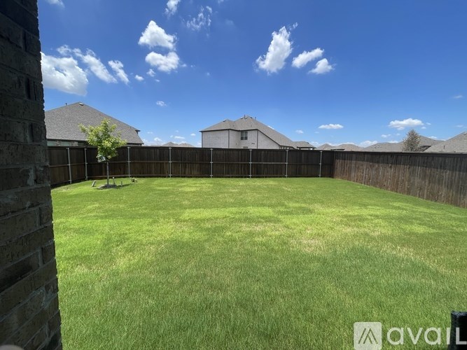 A backyard with a wooden fence and a house in the background.