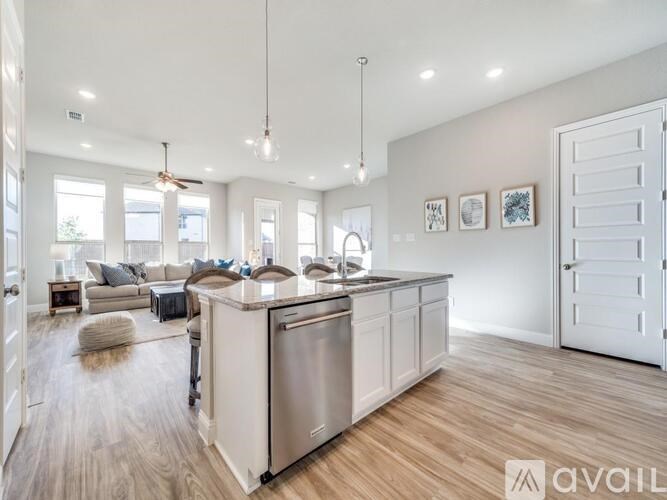 A modern kitchen with a granite countertop and a TV mounted above the sink.
