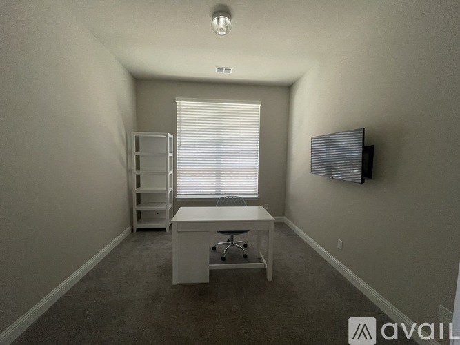 A room with a desk and a window with blinds.