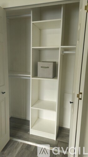 A white closet with shelves and a box on the top shelf.