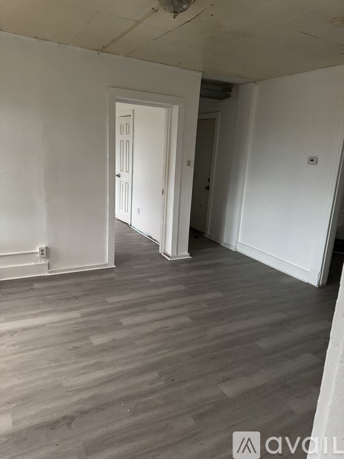 A room with a white door and wooden flooring.