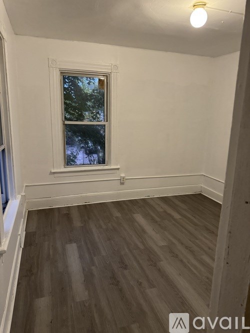 A room with a window and wooden flooring.