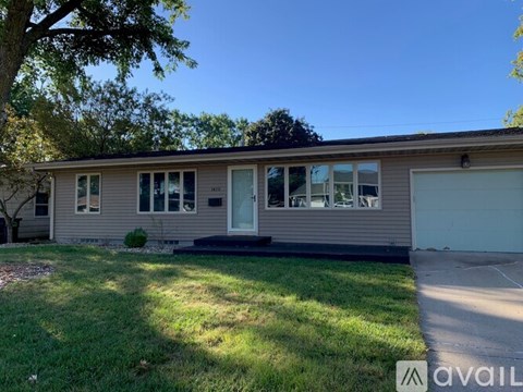 A house with a garage and a tree in front.