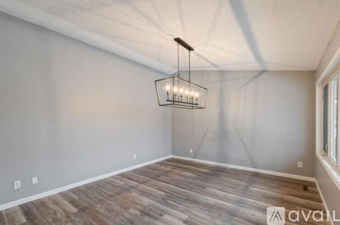 A room with wooden flooring and a hanging light fixture.