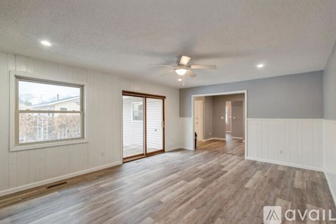 A spacious room with wooden flooring and a ceiling fan.