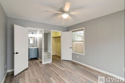 A room with a ceiling fan and a doorway leading to another room.