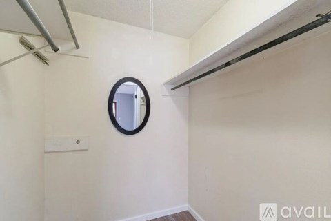 A small room with a round mirror on the wall.