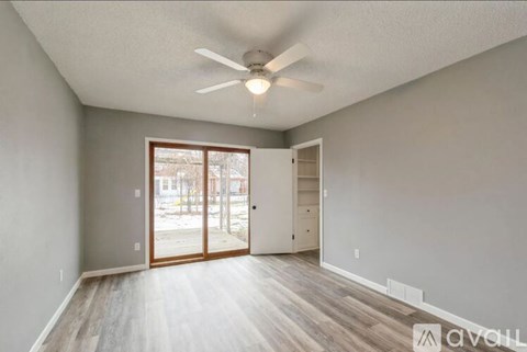 A room with a ceiling fan and a sliding glass door leading outside.