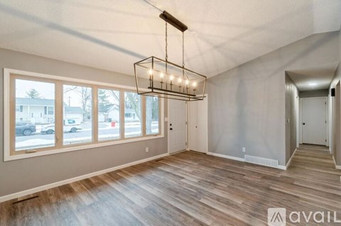 A room with wooden floors and a large window overlooking a street.