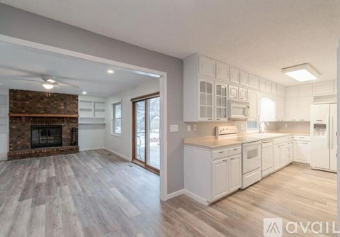 A spacious kitchen with white cabinets and a brick fireplace.