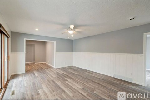 A spacious room with wooden flooring and a ceiling fan.