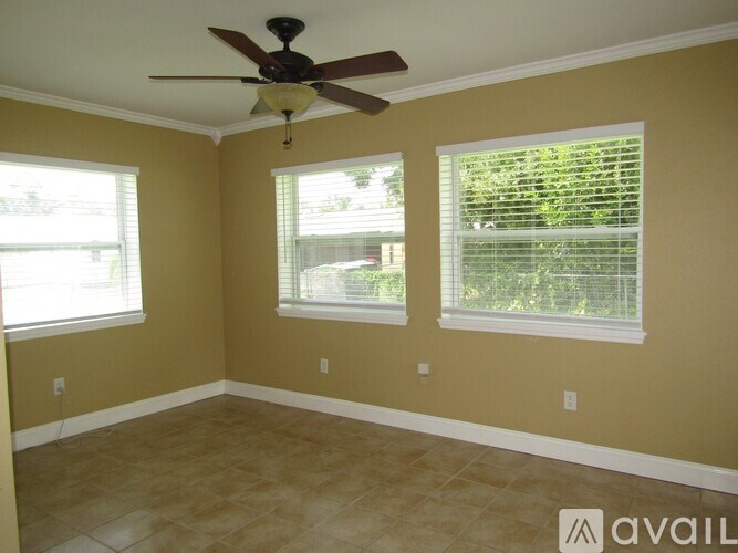 A room with a ceiling fan and two windows.