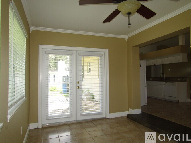 A room with a ceiling fan and sliding glass doors.