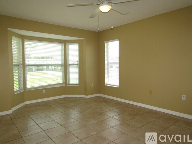A room with a ceiling fan and two windows.
