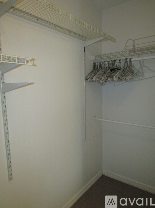 A white closet with clothes hanging on hangers.