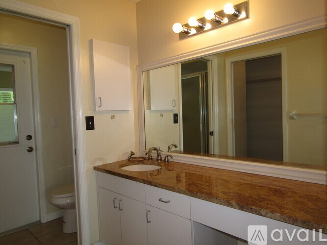A bathroom with a wooden counter top and a mirror with lights above it.