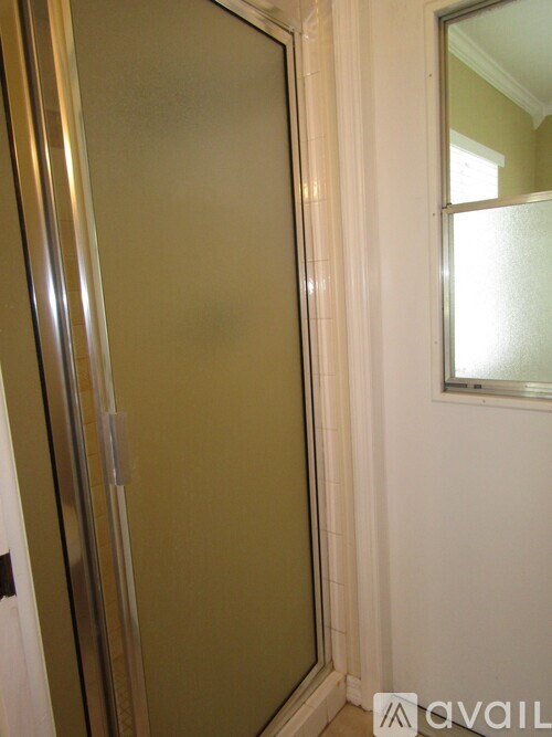A bathroom with a glass shower door and a mirror on the wall.