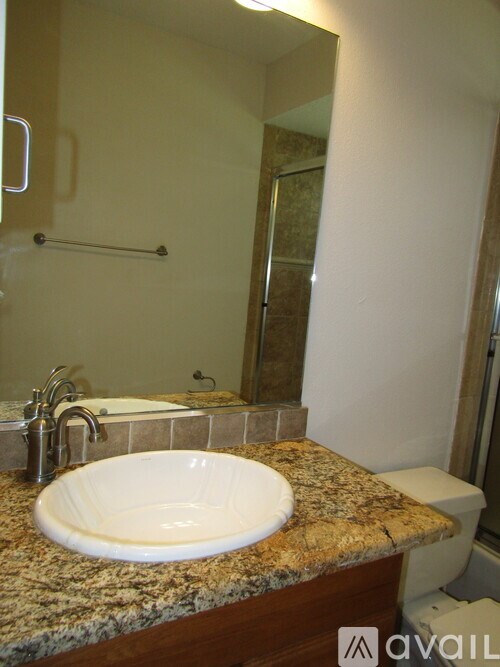 A bathroom with a granite counter top and a white sink.