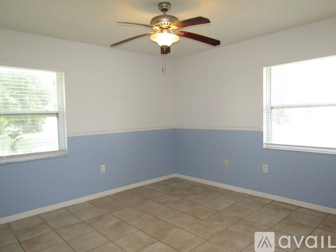 A room with a ceiling fan and two windows.