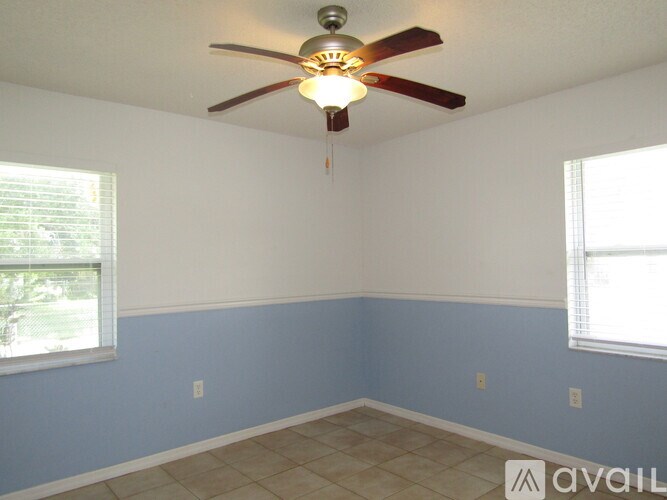 A room with a ceiling fan and two windows.