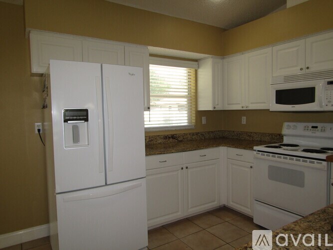 A kitchen with white appliances and cabinets.