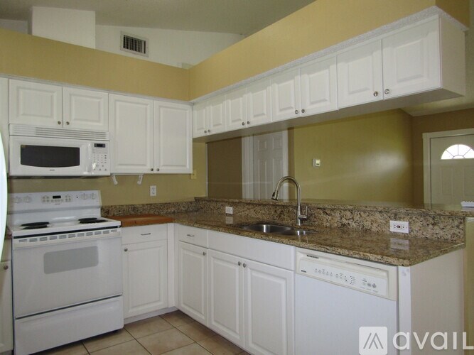 A kitchen with white cabinets and a granite countertop.