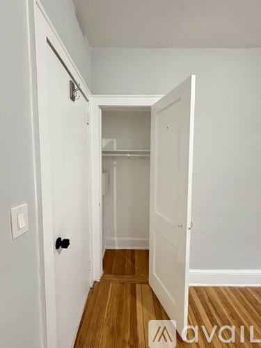 A hallway with a white door and a wooden floor.