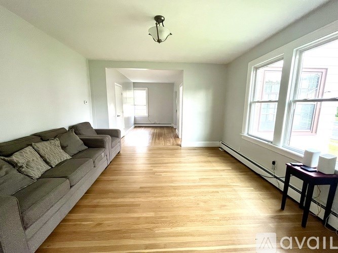 A living room with a grey couch and wooden floors.