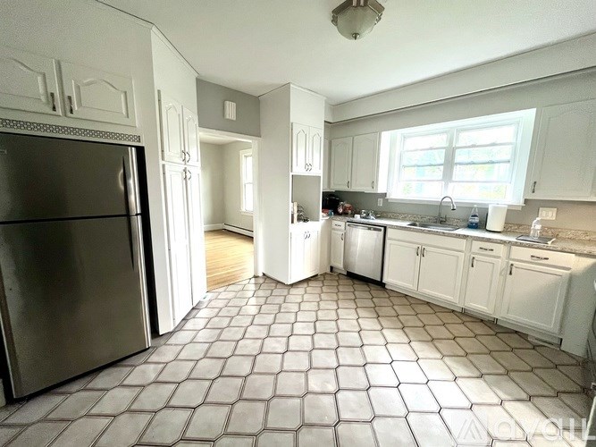 A kitchen with a tile floor and white cabinets.
