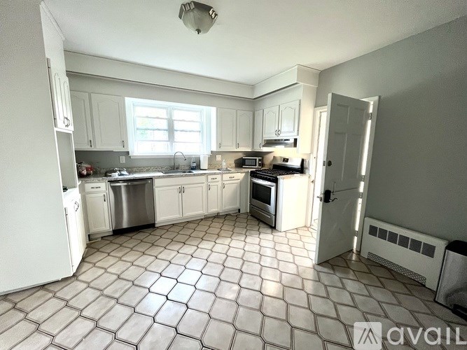 A kitchen with white cabinets and a tiled floor.
