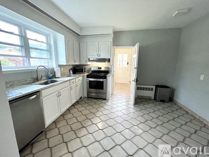A kitchen with white cabinets and a tiled floor.