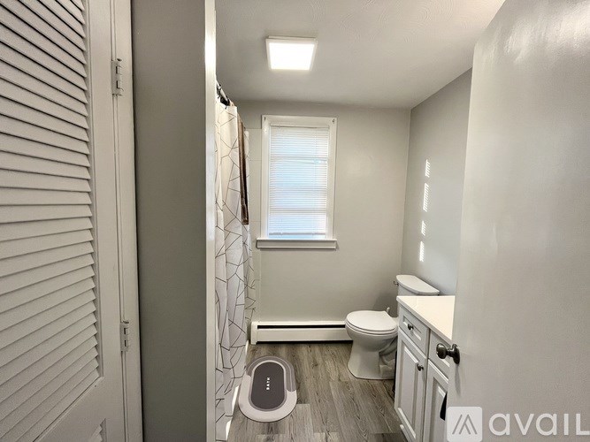 A small bathroom with a toilet, sink, and window.