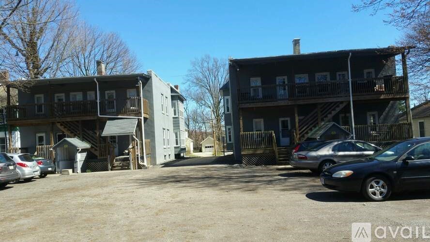 A parking lot with cars and two buildings in the background.
