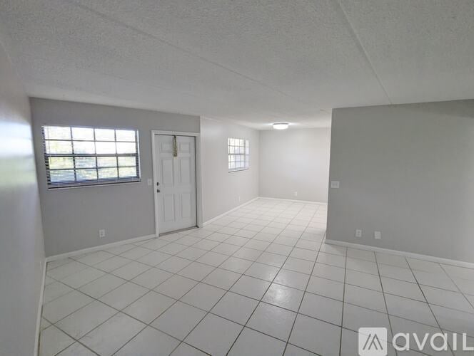 A spacious room with white tile flooring and a single door.