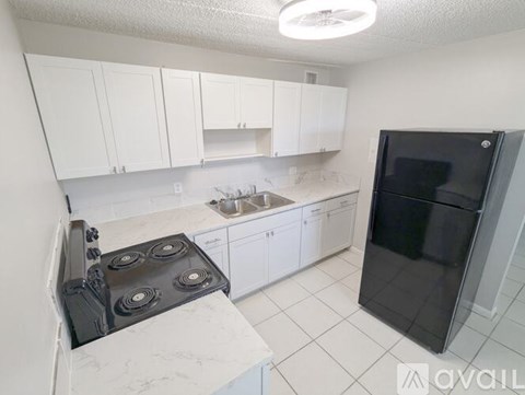 A kitchen with white cabinets and a black refrigerator.